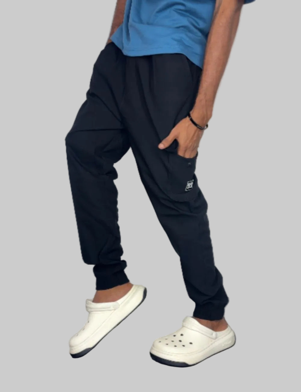 Person wearing black cargo jogger pants and white Crocs on a white background